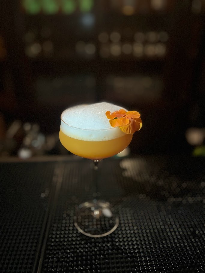orange cocktail with pansy garnish