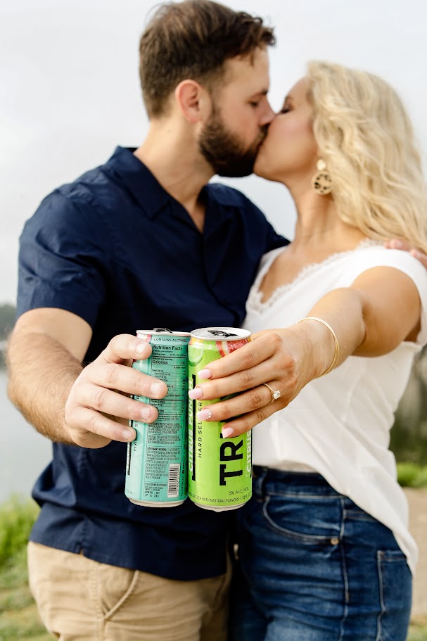 couple kissing while holding spiked seltzers